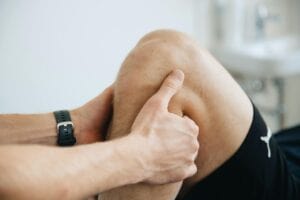 A close-up of an exercise physiologist holding a patient’s knee during a therapy session.