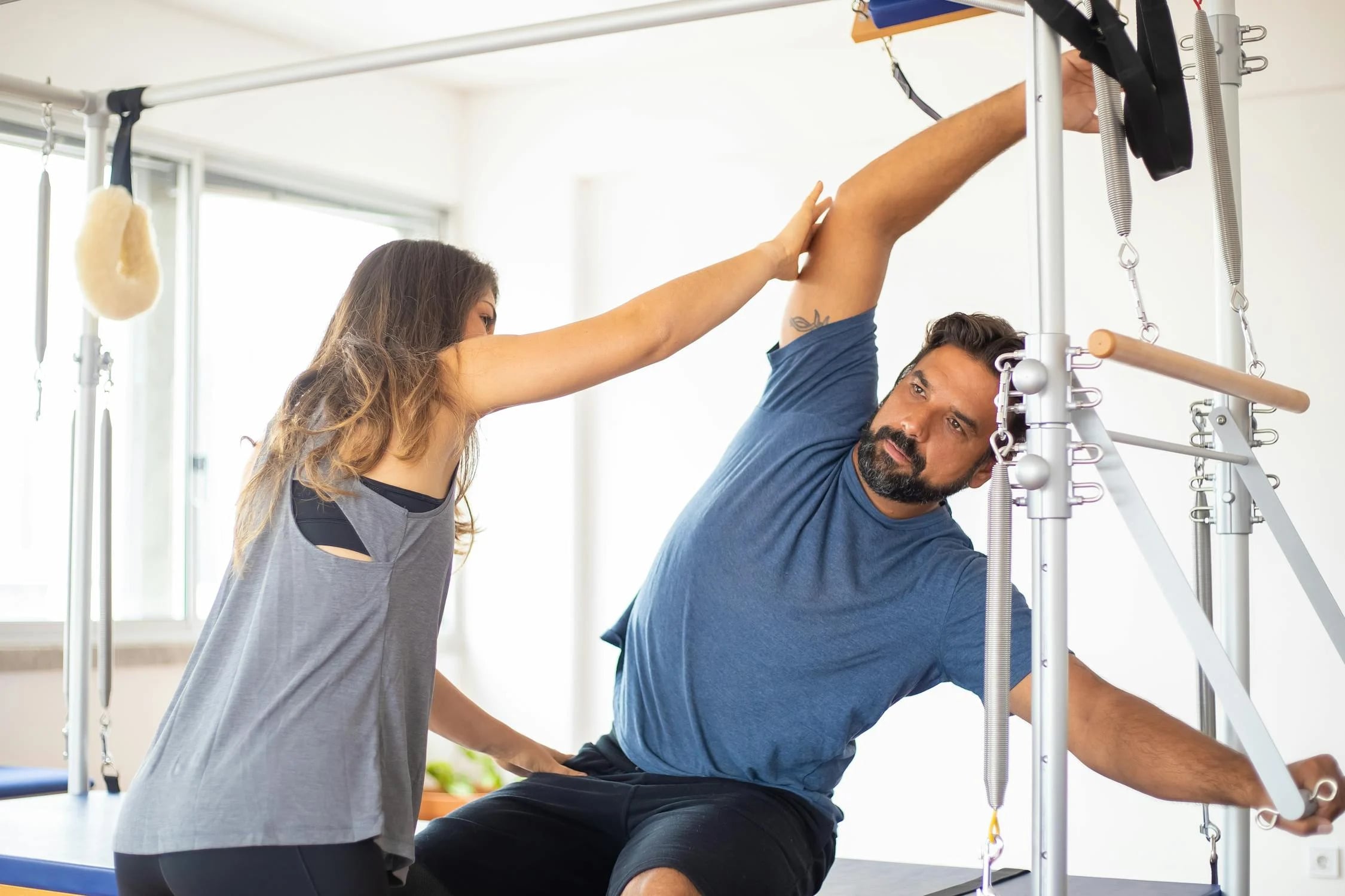 A person performing strength training exercises under the guidance of an exercise physiologist in a clinical setting.