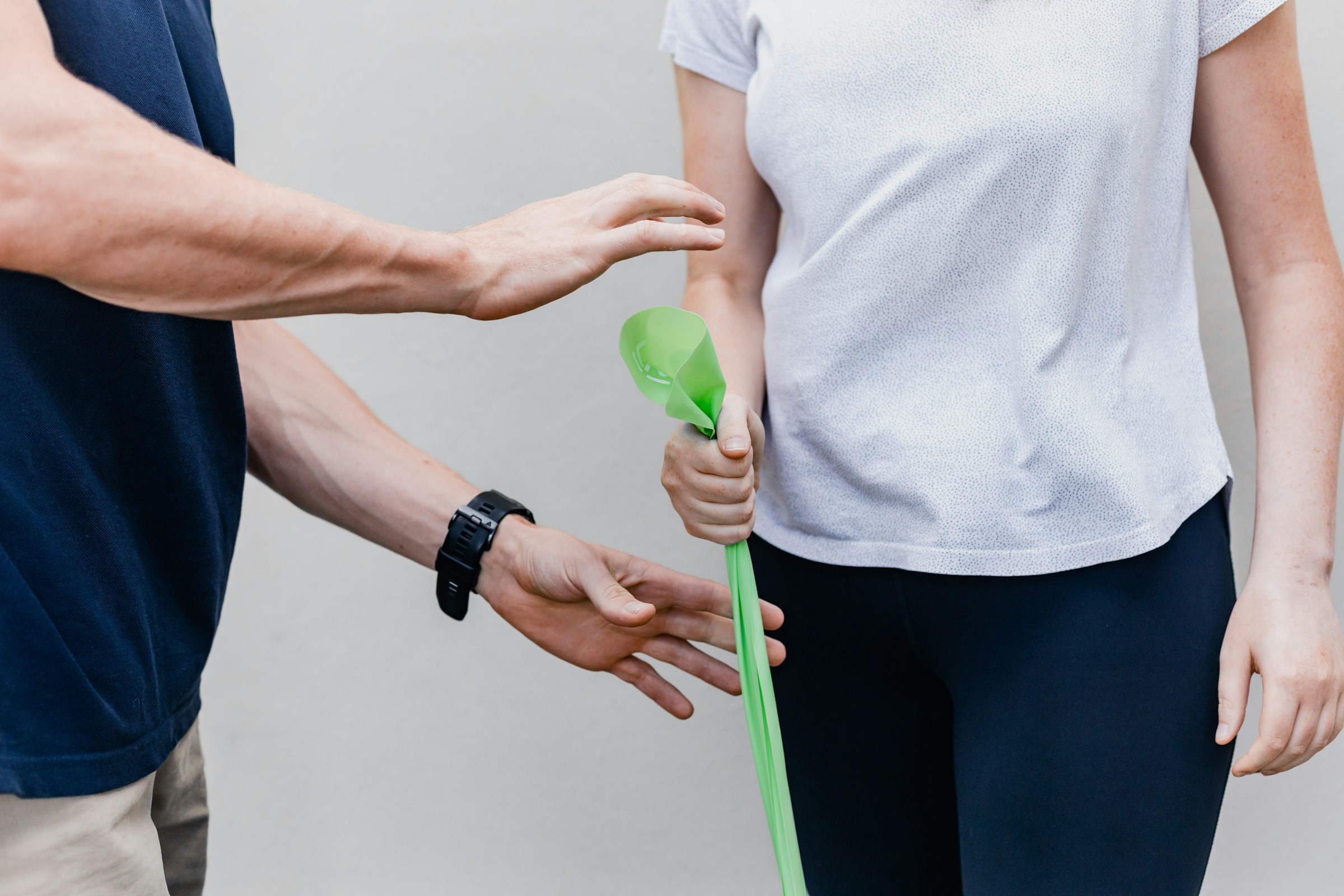 A close-up of a patient gripping a green cloth while performing rehabilitation exercises under the supervision of an exercise physiologist.